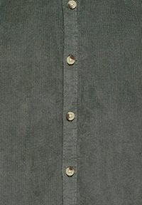 Grijze corduroy overhemd met vijf kleine beige knopen in het midden en een ribbeltextuur. De stof heeft een zachte, matte afwerking.