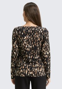 Langärmliges Oberteil in Schwarz mit abstrakten Mustern in Braun und Creme. Mit rundem Halsausschnitt und figurbetontem Schnitt. Weicher, glatter Stoff.