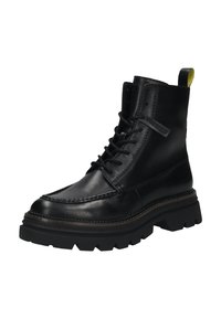 Zwarte leren veterschoen tot de enkel met een dikke robuuste zool en een gele lus aan de achterkant.