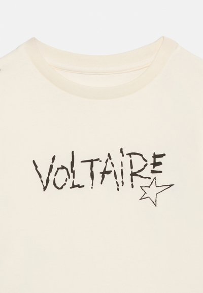 T-shirt couleur crème avec le texte "VOLTAIRE" en noir, style manuscrit irrégulier, et un petit dessin d'étoile en contour sous le "E" près de l'encolure.
