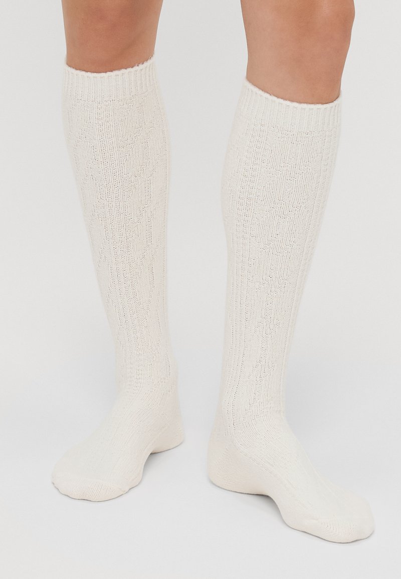 Knee-high cream socks made of textured knit material featuring a diamond pattern, ribbed cuff, and smooth toe area.