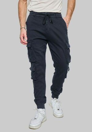 Pantalons cargo bleu marine avec une taille élastique et un cordon de serrage, dotés de poches latérales, de poignets au niveau des chevilles et d'une texture de tissu douce.