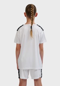 Vitt sporttröja med svarta accenter på axlarna, kombinerad med vita shorts med svarta detaljer, lämplig för idrottsbruk.