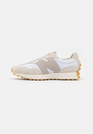 Sneaker med lav profil i beige og hvid med ruskindsoverlejringer, snørebånd foran, gummisål og stor side-logo i neutrale toner.