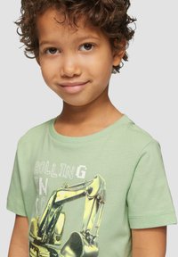 Lichtgroen katoenen T-shirt met een grafisch ontwerp van een graafmachine en vetgedrukte tekst. Korte mouwen, ronde hals en zachte textuur.