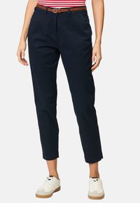 Mörkblå bomullsbukser med avslappnad passform, avsmalnande ben och ett brunt läderbälte. Matchas med vita sneakers för en avslappnad look.
