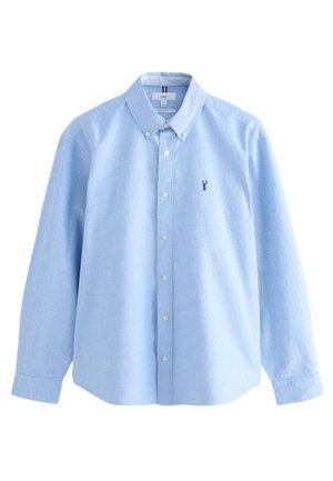 Világoskék gombos inget, sima anyagból készült. Gallérral, hosszú ujjal és egy kis hímzett logóval a mellkasán.