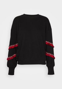 Svart sweatshirt med nedhängda axlar, långa ärmar och röda fransdetaljer längs ärmarna. Tillverkad av mjukt tyg med en avslappnad passform.