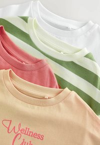 Vier ordentlich gefaltete T-Shirts in Beige, Pink, grün-weiß gestreift und einfarbig Weiß, wobei Kragen und oberer Vorderteil sichtbar sind.