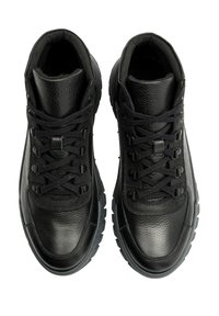 Czarne skórzane trampki z teksturowanym materiałem, okrągłym noskiem, sznurowanym zapięciem oraz masywną podeszwą z ciemnymi akcentami, widok z góry.