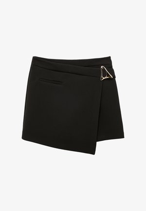 Zwarte asymmetrische minirok met een decoratieve gouden driehoekige gesp aan de rechtervoorzijde en een enkele paspelzak aan de linkerkant.