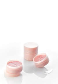 Trois pots ronds roses de patchs pour les yeux Abib PDRN retinal, présentant une texture lisse et un marquage discret, avec un patch visible dans un des pots.