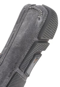Zapato de ante gris con una superficie texturizada, que presenta una suela de goma gruesa y acentos grises en contraste. Detalle de costura visible a lo largo del borde.