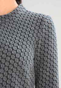 Suéter gris con un diseño de diamante texturizado, con un cuello alto y mangas largas, confeccionado en una suave tela de punto.