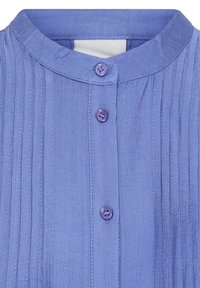Chemise bleu clair avec un col rond, des plis cousus verticaux et trois boutons assortis sur le devant.