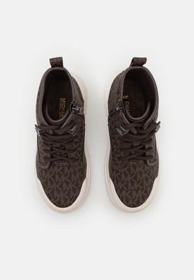 Brown patterned sneakers with a textured fabric upper, round toe, lace-up design, and white rubber soles. Includes dual zip details.
