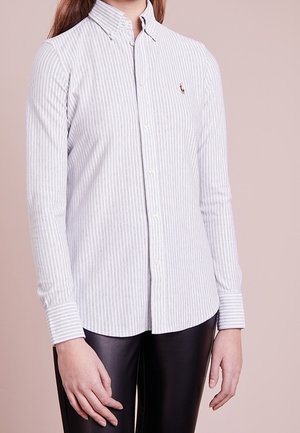 Wit en lichtblauw verticaal gestreept overhemd met lange mouwen en knopen, gedragen met een zwarte broek, bij een persoon met lang bruin haar.