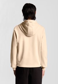 Beige Kapuzenpullover mit großer Kapuze, langen Ärmeln, gerippten Bündchen und glatter Textur, rückwärts getragen, sodass keine vorderen Details sichtbar sind.