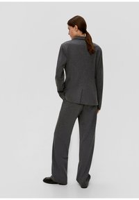 Costume ajusté gris foncé avec une veste cintrée et un pantalon à jambes larges, featuring un tissu texturé et un design de col revers standard, vue de dos.
