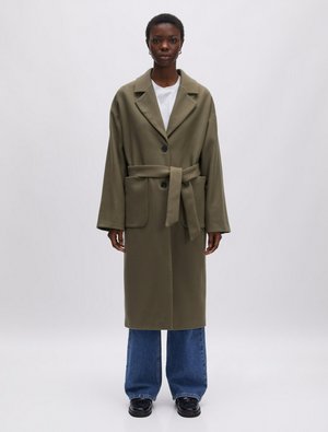 Olijfgroene oversized jas met een ingesneden kraag, enkele knoopsluiting, zijzakken en een bijpassende riem, gedragen over een wijde jeans.