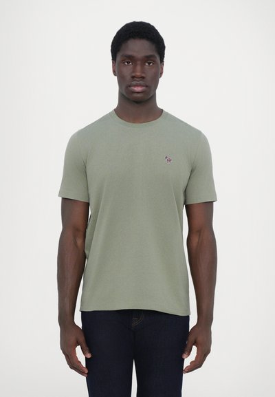 T-shirt à manches courtes en coton vert olive avec un col rond et un petit logo brodé sur la poitrine gauche. Tissu uni et texturé.