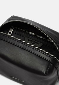 Pouch in pelle nera con superficie testurizzata, dotata di una cerniera argentata e di un'etichetta interna con marchio, che presenta un design semplice e rettangolare.