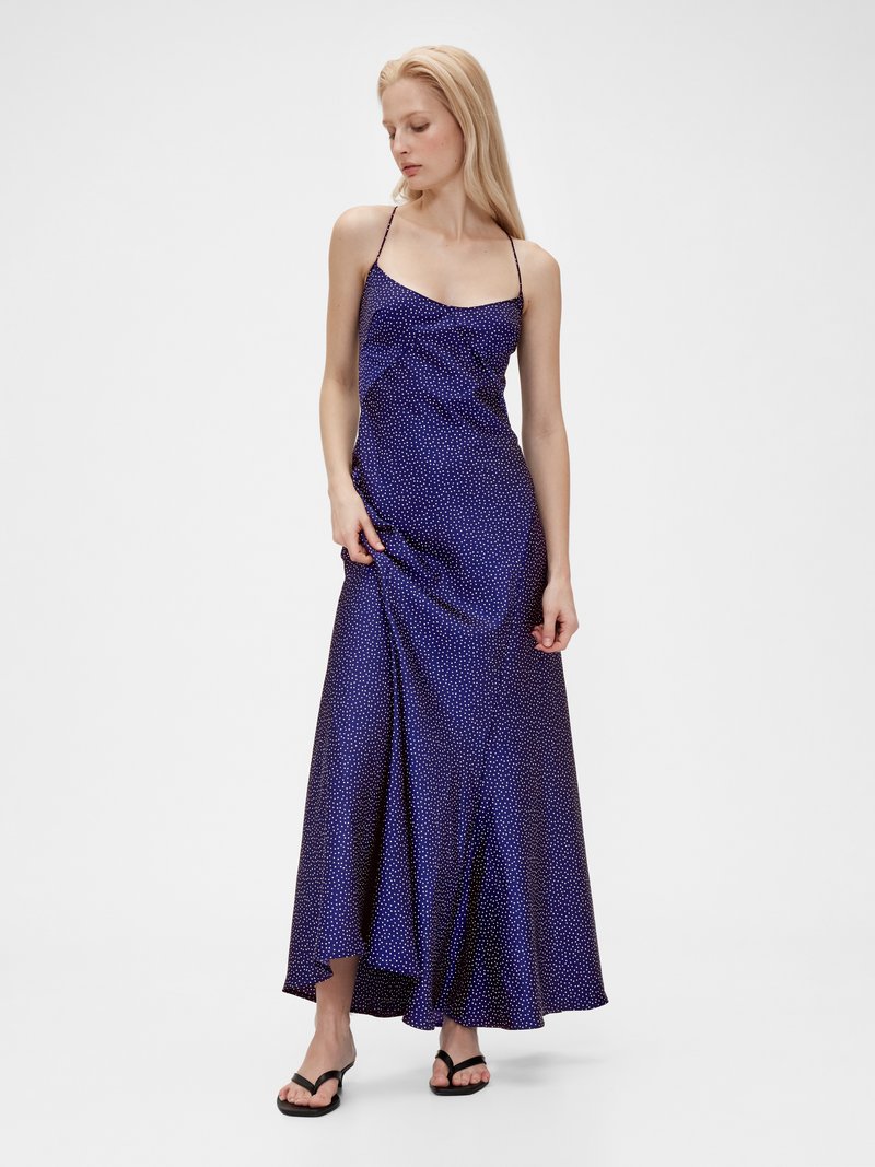 Satin Maxi-Kleid in Dunkelviolett mit weißen Punkten. Verfügt über dünne Träger, ein tailliertes Oberteil und einen fließenden A-Linien-Rock.