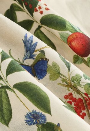 Stof met een botanische print van groene bladeren, rode appels, blauwe bloemen en vlinders op een textuurlijke crèmekleurige achtergrond.