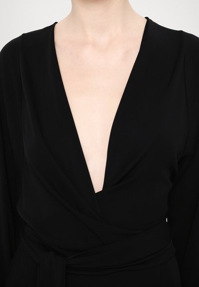 Svart omlottklänning med djup V-ringning, långa ärmar och ett tygbälte i midjan, gjord av ett slätt material med mjuk textur.