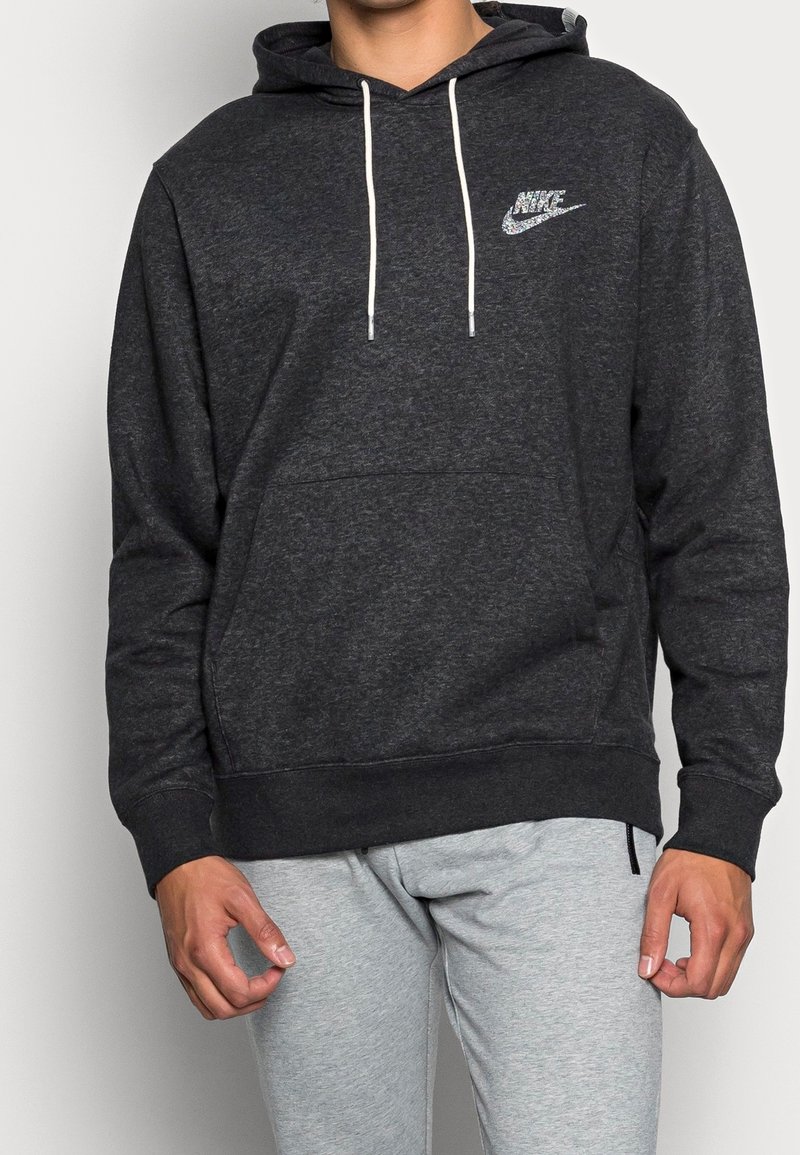 Grå hoodiet tillverkad av mjukt tyg med en framficka, dragsko huva och en liten reflexlogga från Nike på bröstet.