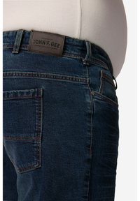 Jeans in denim blu scuro con etichetta in pelle, design a cinque tasche e dettagli di cucitura a contrasto.