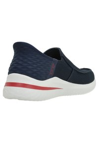 Tengerészkék slip-on cipő texturált felsőrésszel, fehér középtalppal és piros díszcsíkkal. Alacsony sarkú és légáteresztő hálós kialakítással rendelkezik.