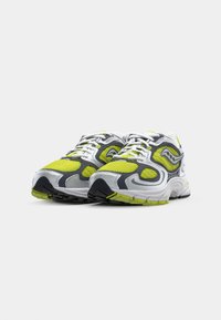Gray and white athletic shoes featuring a mesh upper with neon yellow accents and black rubber soles, showcasing a streamlined design.
