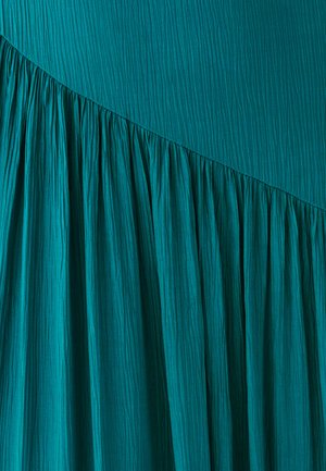 Vestido azul verdoso con pliegues verticales y un diseño fluido. Presenta una superficie lisa y una costura recogida y curva en la parte inferior.