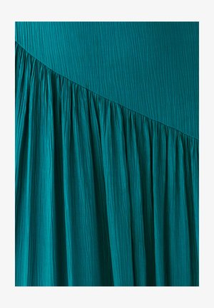 Vestido azul verdoso con pliegues verticales y un diseño fluido. Presenta una superficie lisa y una costura recogida y curva en la parte inferior.