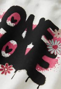 Zwart grafisch print op een witte stof, met roze harten en bloemenaccenten in zilver en rode glitter. Druipende verf effect zichtbaar.
