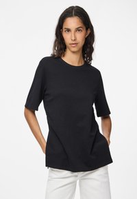 Sort kortærmet t-shirt lavet af bomuld, med rund halsudskærning og en afslappet pasform. Let buet kantdetalje nederst.