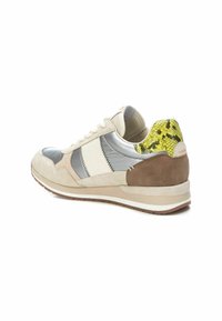 Zapatilla con parte superior de nobuk y malla en beige, gris y oliva, con un acento de piel de serpiente amarilla texturizada en el talón y suela blanca.