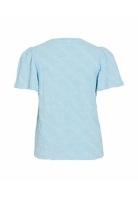 Ανοιχτό μπλε τοπ με κοντά μανίκια, υφασμένο με λουλουδένιο σχέδιο και ελαφρώς φουσκωτά μανίκια, εμφανιζόμενο από πίσω.