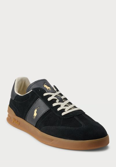 Adidași din suede negru și gri, cu talpă din cauciuc, închidere cu șireturi și detalii cu logo auriu pe lateral.