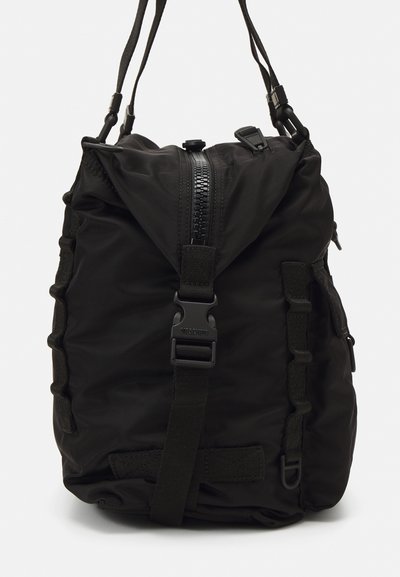 Rucsac negru din nylon cu închidere prin șnur, dotat cu un fermoar mare, bretele ajustabile și curele laterale pentru compresie.