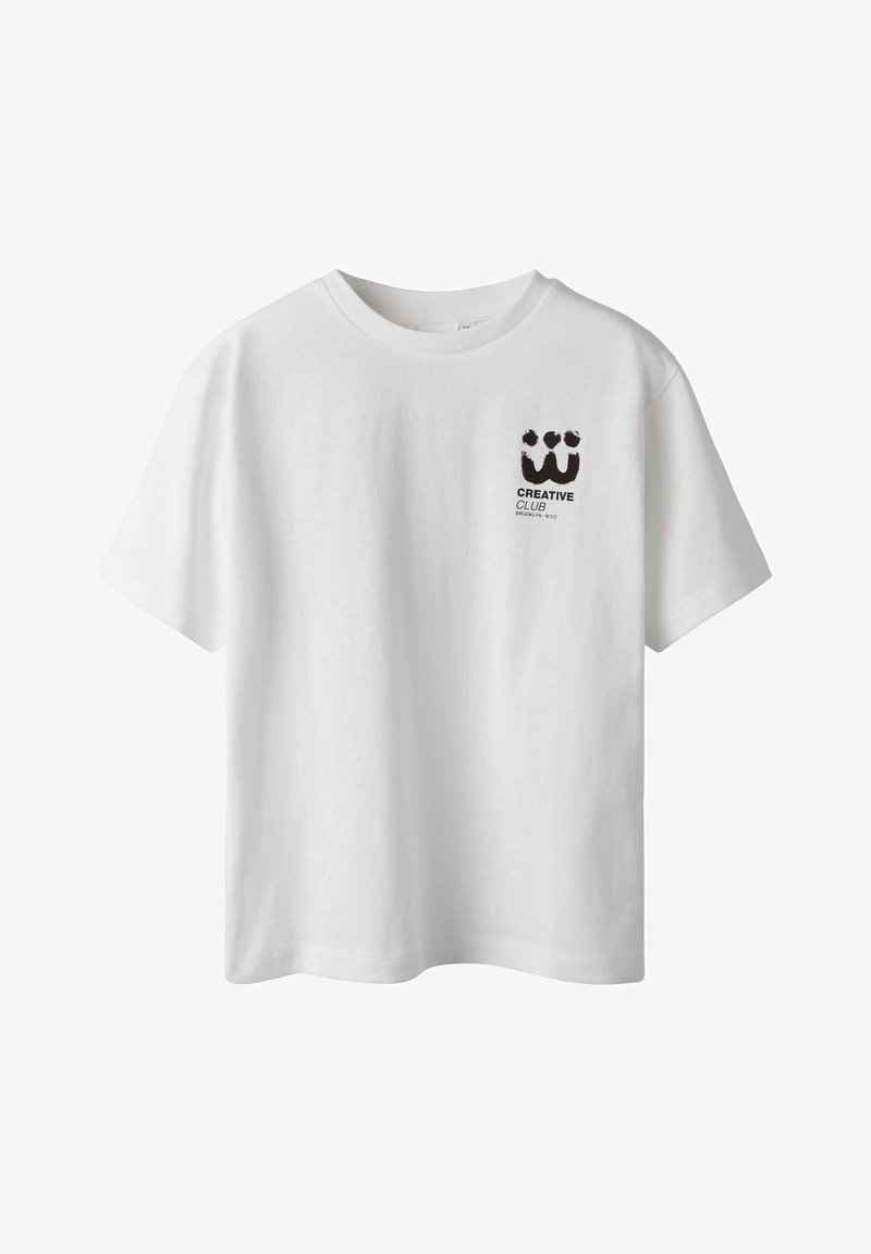 Balta kokvilnas T-kreklā ar īsām piedurknēm, apaļu kakla izgriezumu un melnu grafiku "CREATIVE CLUB" kreisajā krūšu daļā.