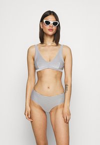 Biquíni listrado em cinza e branco com parte superior tipo bralette triangular e cuecas de cintura alta, feito de um tecido macio e elástico.