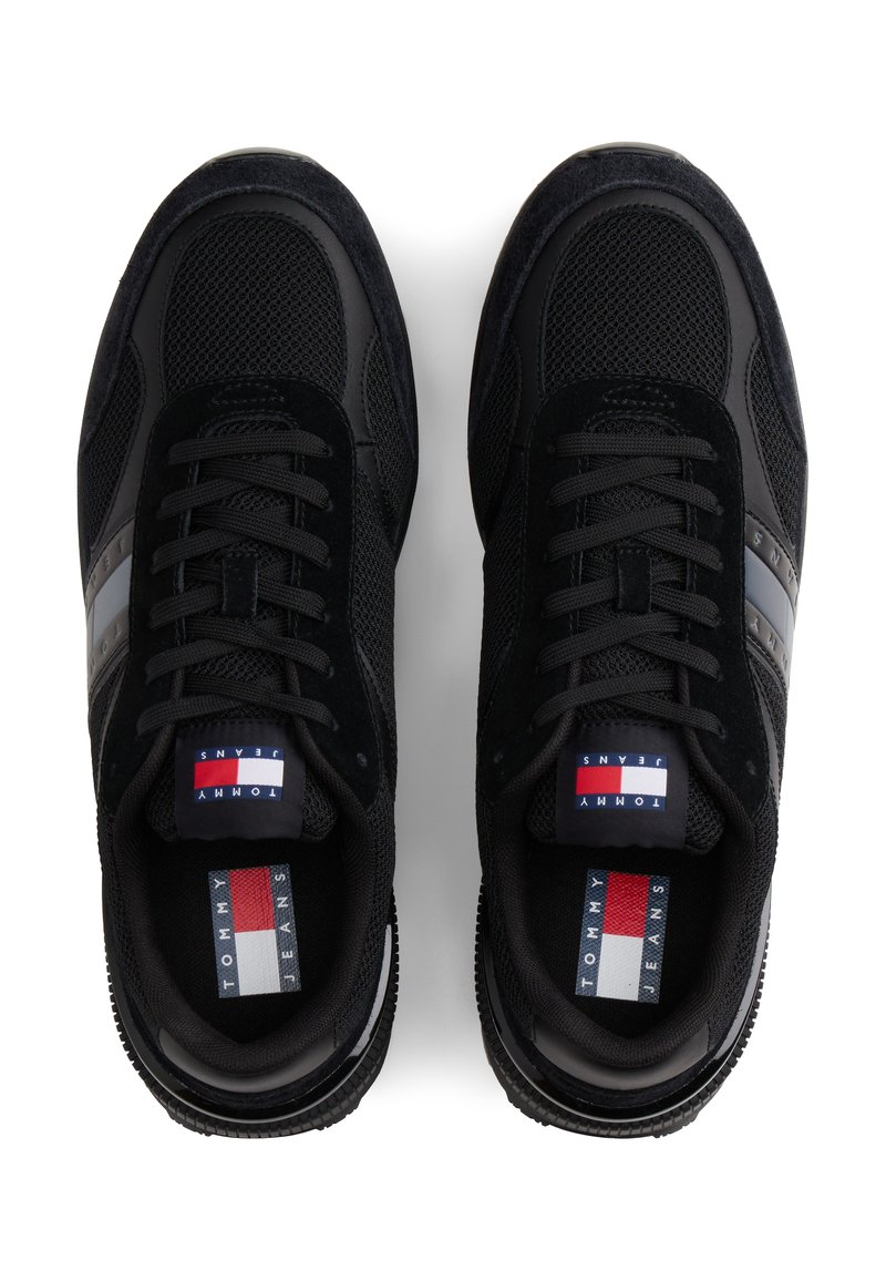 Zapatillas negras con una combinación de materiales de malla y ante, con una franja de contraste y detalle de logo en la lengüeta. Suela texturizada.