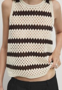 Top in crochet con strisce orizzontali alternate di crema e marrone scuro, con una texture a rete aperta, scollatura rotonda.