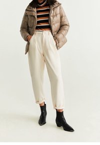 Beige pufferjakke med pelsforet krave, stribet langærmet top, cremede tapered bukser og sorte ankelstøvler med spidse tå.
