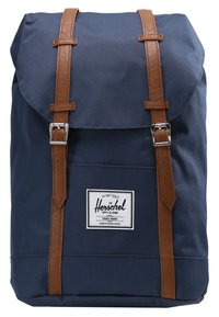 Morski plecak materiałowy z brązowymi skórzanymi paskami, z magnetycznym zapięciem klapy oraz przednią etykietą z logo "Herschel". Gładka tekstura.