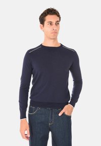 Maglione blu navy realizzato in morbido tessuto, con scollatura rotonda, maniche lunghe e cuciture decorative bianche sulle spalle.