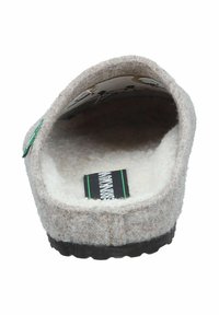 Beige felt slipper with soft, fluffy lining. Features a round opening, flat black rubber sole, and an inner label with green and black accents.