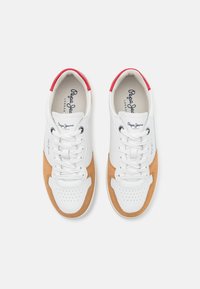 Paire de baskets en cuir blanc avec des empiècements en daim marron clair et des accents rouges au talon, vues de dessus sur fond blanc.